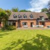 Spacious brick house with large garden and patio furniture under a clear sky in a suburban area of the UK
