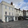 Charming UK high street with historic buildings, shops, and a parked car on a cloudy day
