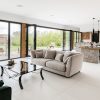 Modern open-plan living room with large windows, elegant sofas, and a stylish kitchen overlooking a scenic landscape
