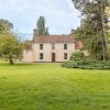 Charming rural house with a tiled roof surrounded by lush greenery and trees in a serene countryside setting
