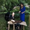 Man and woman conducting soil experiment in a garden setting with camera equipment nearby