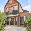 Charming two-storey brick house with lush garden in the UK, featuring large windows and a welcoming entrance path