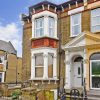 Victorian-style brick house with ornate columns and large bay window in a UK residential neighbourhood
