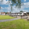 Rural equestrian property with spacious barn and green lawns under a blue sky in the UK countryside