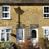 Charming English terraced cottages with brick facades and white windows, surrounded by a neatly kept garden
