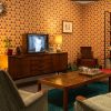 Cosy retro living room with vintage TV, patterned wallpaper, and mid-century furniture for a nostalgic vibe