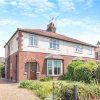 Semi-detached brick house with arched windows and front garden on a sunny day in a residential area