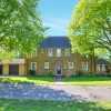 Brick house with trees and driveway under a bright blue sky in UK residential area