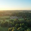 Aerial view of an English estate surrounded by lush greenery at sunset in the countryside