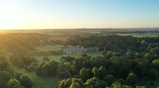 Aerial view of an English estate surrounded by lush greenery at sunset in the countryside