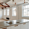 Modern kitchen with exposed beams and ample natural light from large windows in an industrial-style loft conversion