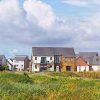 Modern UK homes with lush greenery under a blue sky, showcasing contemporary architecture in a suburban setting