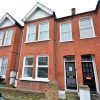 Red brick terraced house with bay windows and white trim in a residential UK neighbourhood