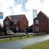 Modern English housing estate with brick homes, flags, and visitor parking at Tilia Homes development in the UK