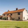 Traditional English countryside house with red-tiled roof and garden under clear blue sky
