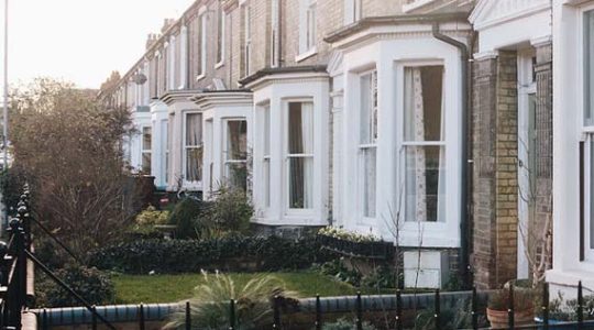 Row of traditional British terraced houses with gardens and sunset lighting