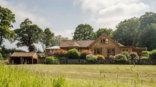 Charming country house in lush green landscape with trees and shrubs, brick architecture and serene countryside setting