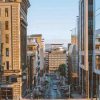 City street flanked by modern and historic buildings under a clear blue sky in the daytime urban setting