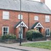 Red brick semi-detached houses with garden space in a residential UK street
