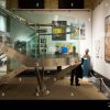 Modern museum interior with spiral staircase, artwork, and sculptures in a well-lit exhibition space