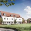 Modern UK housing development with terraced and detached houses in a green residential area under a blue sky