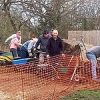 Group of volunteers working on a community garden project with wheelbarrows and tools in an outdoor setting