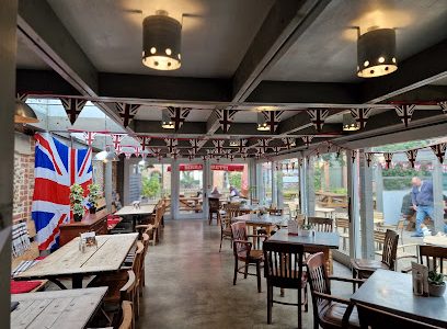 UK-themed cafe interior with Union Jack decor, wooden tables, and outdoor garden view through glass windows