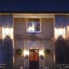 Historic English inn lit up at night, showcasing warm lighting and classic architecture, surrounded by benches and greenery