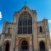 Front view of a historic cathedral with ornate windows and stone carvings under a clear blue sky in the UK