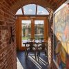 Dining area with metal chairs and wooden doors in a brick-walled space, natural light streaming in from outside
