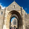 Historic cathedral entrance under a blue sky with intricate stonework and statues in a traditional UK setting
