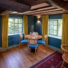Cosy dining room with wooden furniture, blue chairs, yellow curtains and exposed beams, natural light through windows
