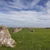 Ancient stone ruins on green countryside landscape under a cloudy blue sky in the UK
