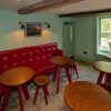 Cosy café interior with red bench seating, round wooden tables, and green walls in a bright room overlooking a garden