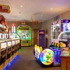 Bright UK arcade with colourful game machines and neon lights, including a Jurassic Park themed area
