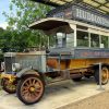 Vintage London road car with classic advertisements, showcasing historical automotive design under a shelter