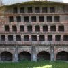 Historic brick dovecote structure with multiple square openings set against a grassy background