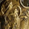 Ancient gold relief depicting a classical warrior with detailed armour and dynamic posture in a historical style