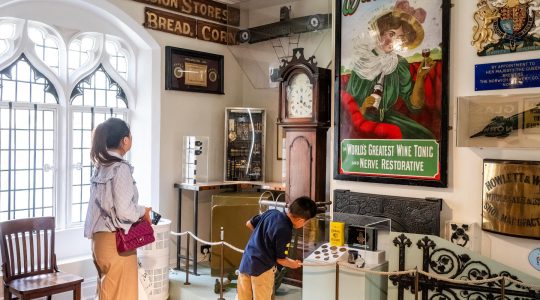 Visitors exploring historical museum exhibits with vintage signs and collectibles