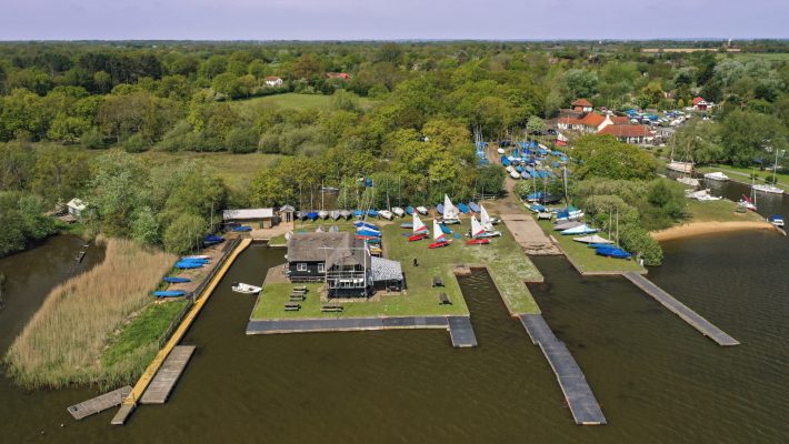 Aerial view of a vibrant sailing club with boats on a lush landscape by the water in the English countryside