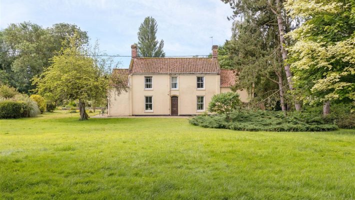 Charming rural house with a tiled roof surrounded by lush greenery and trees in a serene countryside setting