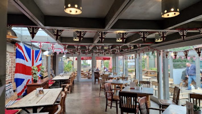 UK-themed cafe interior with Union Jack decor, wooden tables, and outdoor garden view through glass windows