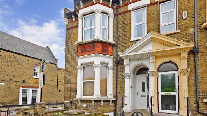 Victorian-style brick house with ornate columns and large bay window in a UK residential neighbourhood