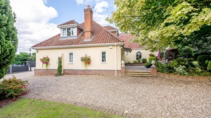 Charming countryside house with red tiled roof surrounded by lush garden landscaping and gravel driveway