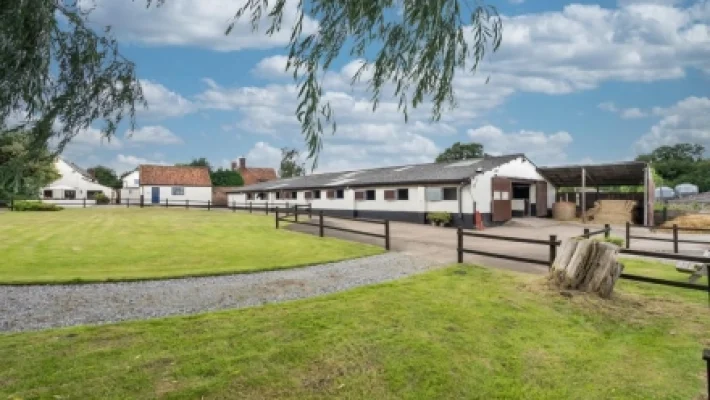 Rural equestrian property with spacious barn and green lawns under a blue sky in the UK countryside