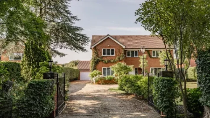Charming brick house with ivy, surrounded by trees, on a sunny day in the English countryside
