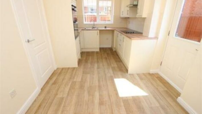 Bright kitchen with wooden flooring, cream cabinets, and sunlight through windows for a fresh, inviting atmosphere