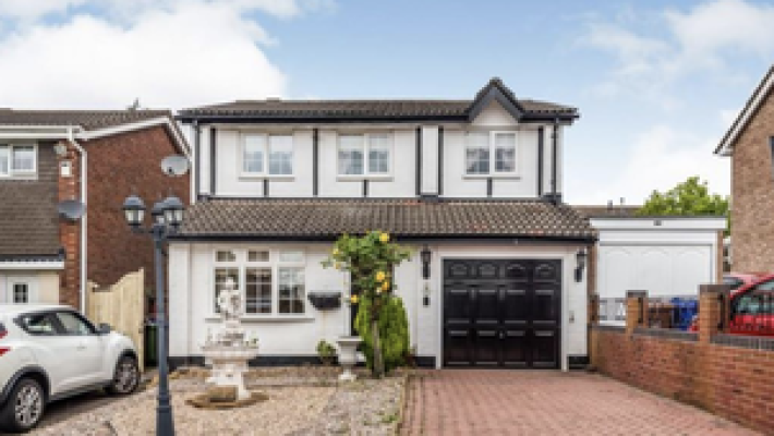 Two-storey detached house with a garden, garage, and driveway on a residential street in the UK