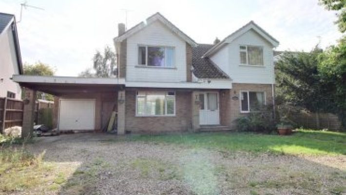 Detached two-storey house with garage and gravel driveway in suburban UK neighbourhood, surrounded by greenery
