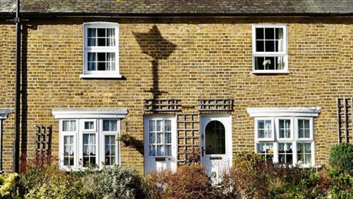 Charming English terraced cottages with brick facades and white windows, surrounded by a neatly kept garden